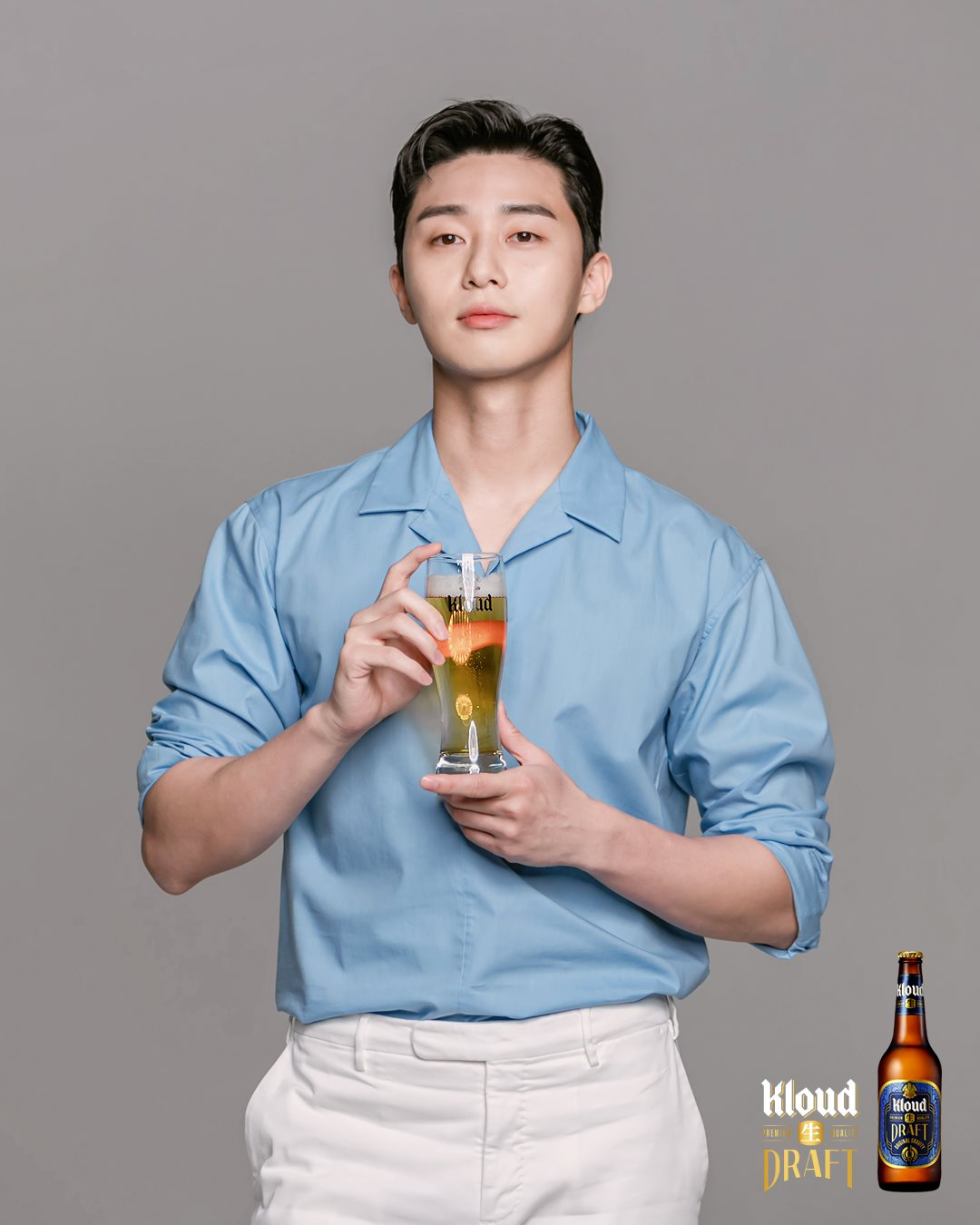 穿藍色襯衫和白色褲子的人手持啤酒杯展示Kloud生DRAFT啤酒