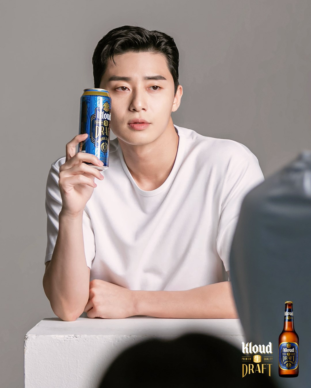 身穿白色T恤的人手持Kloud生DRAFT啤酒罐坐在白色桌子旁