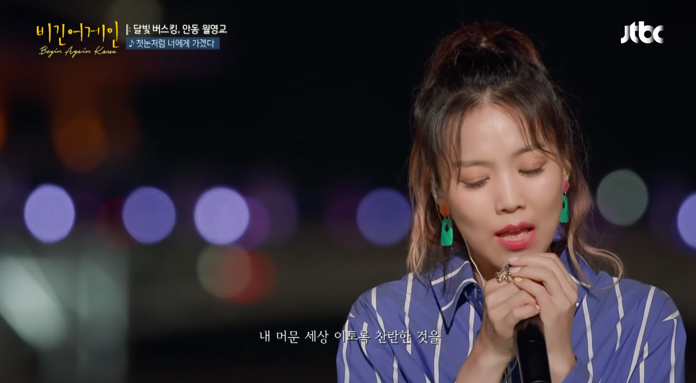 《Begin Again Korea》中夜景背景下，歌手正在深情演唱的畫面。