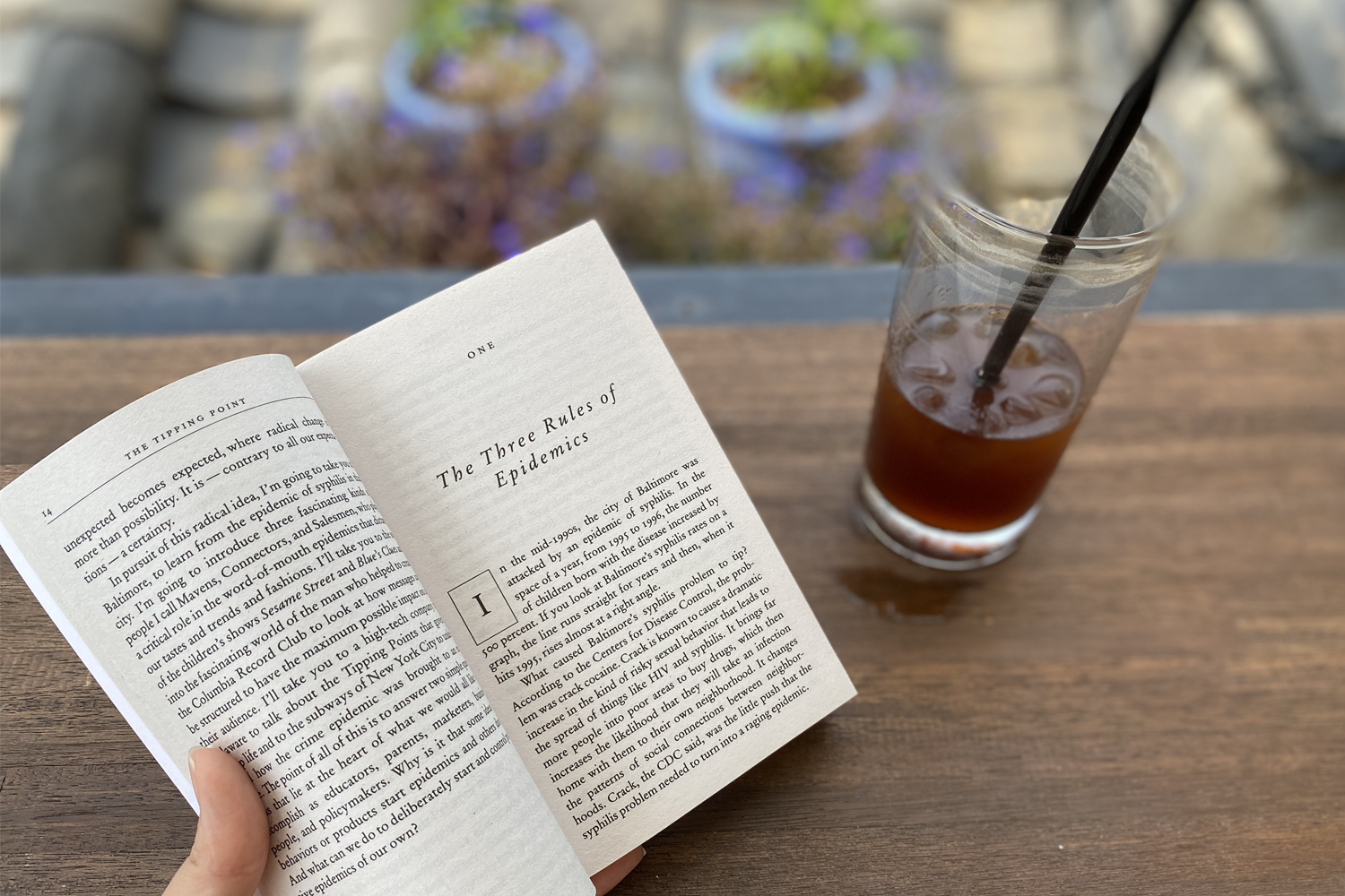 一杯冰咖啡和一本書擺放在木桌上，背景是Cafe58.4露臺上的韓屋屋頂美景。