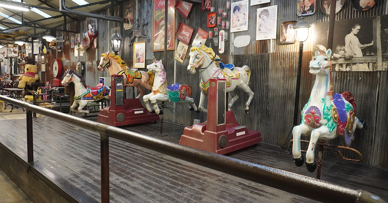 มุมหนึ่งในคาเฟ่โชยางบังชิก อินชอน เกาหลีใต้ มีม้าโยกเก่าแก่สีสันสวยงามหลากหลายตัว ด้านหลังมีภาพและของตกแต่งสไตล์วินเทจติดบนกำแพง