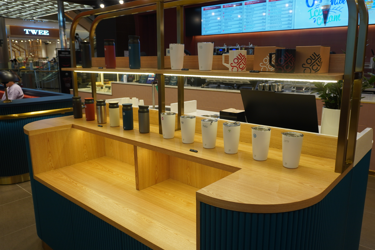 JYP SOULCUP Cafe 展示櫃，陳列各種具有JYP標誌的時尚保溫杯