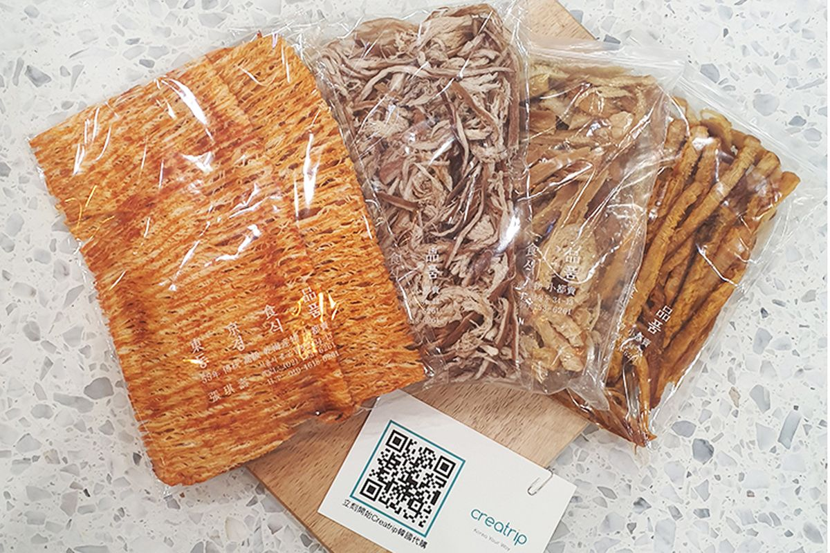 南大門市場老爺爺的原味、辣味及烤奶油魷魚乾的多樣性展示在木砧板上。