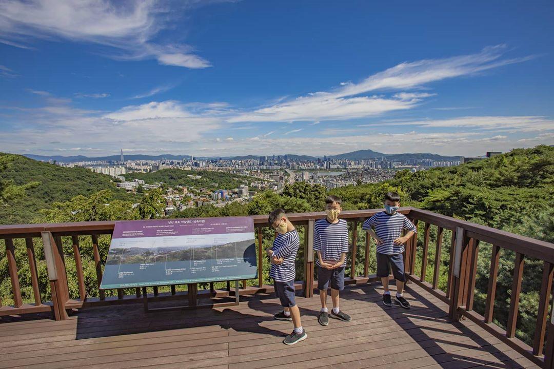 宋一國的三胞胎在南山觀景台上認真地閲讀資訊牌，探索首爾的美景。