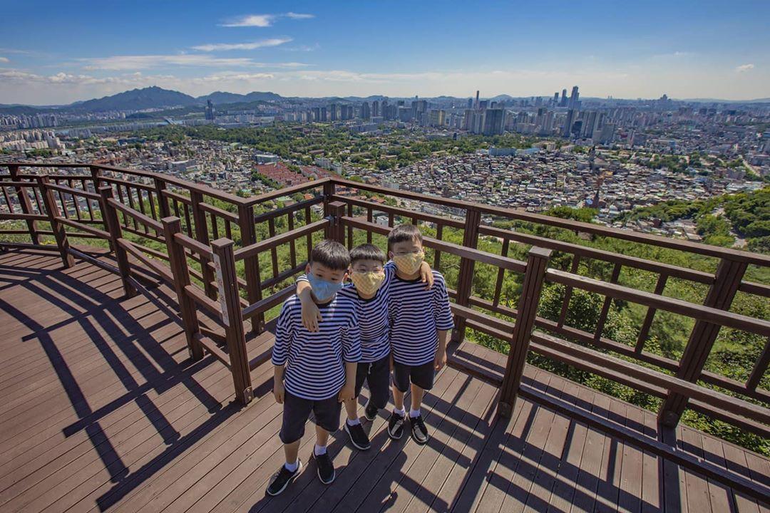 宋一國的三胞胎手搭手站在南山觀景台，兄弟之間的親密互動。