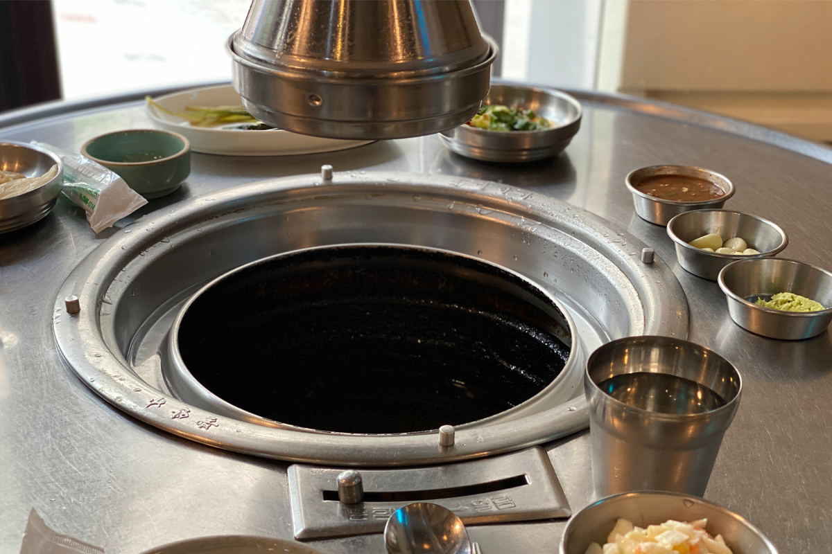 燒肉店內的烤肉桌，配有一些小碟調味品和金屬杯。