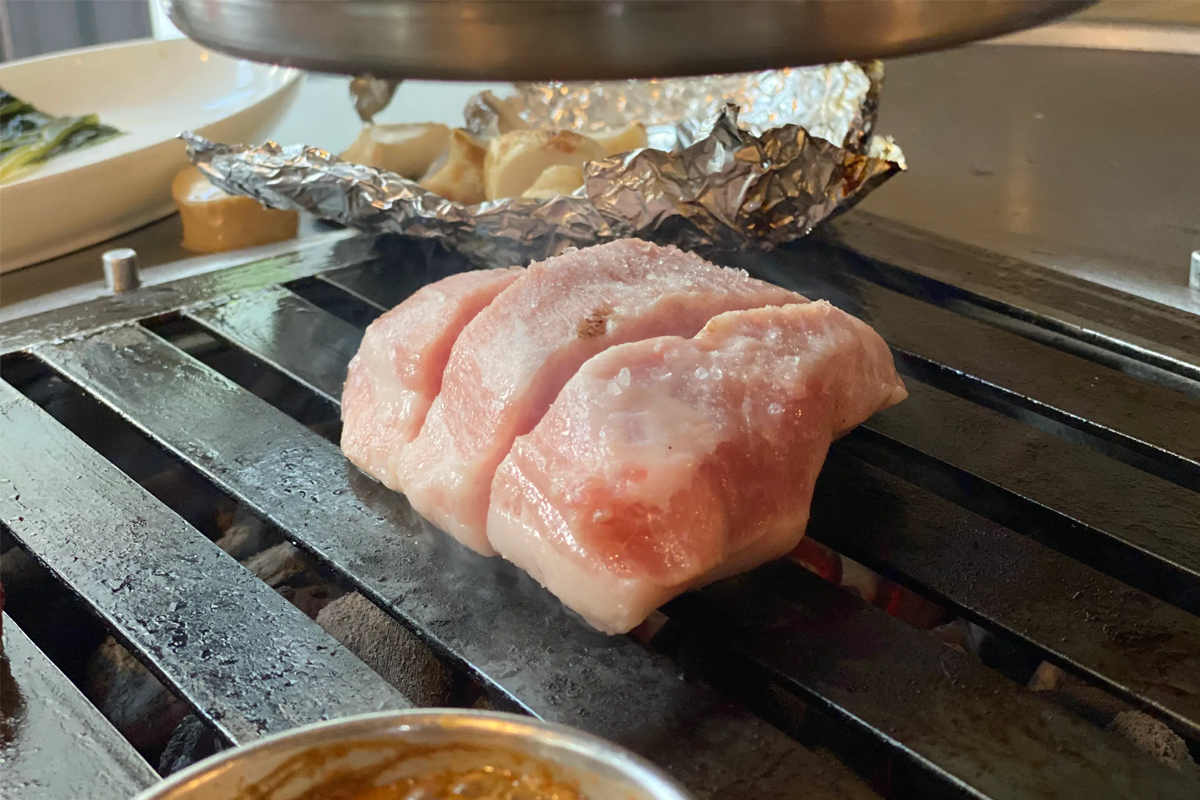 首爾受歡迎的三層肉店，烤制中的豬頸肉