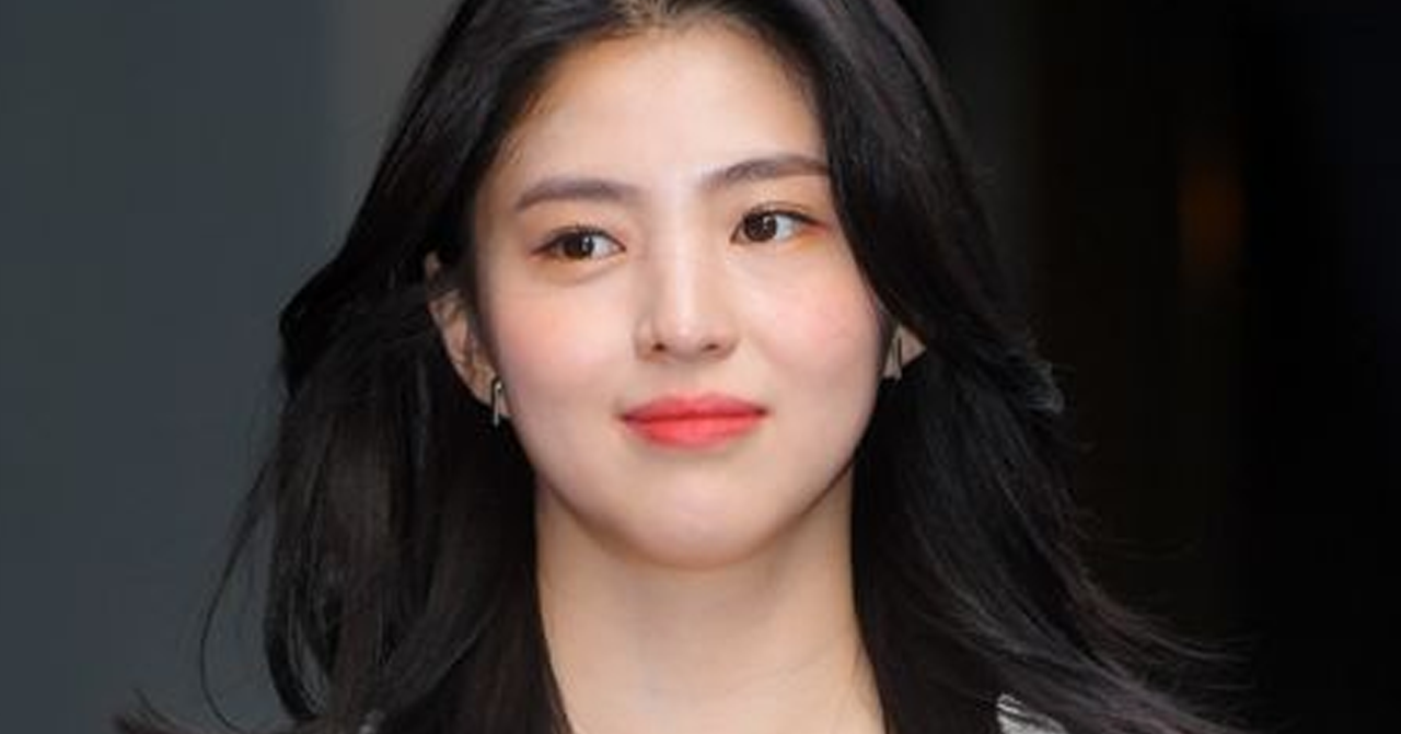 韓素希在室外身穿白色西裝，背景是模糊的建築物和暗色外牆。