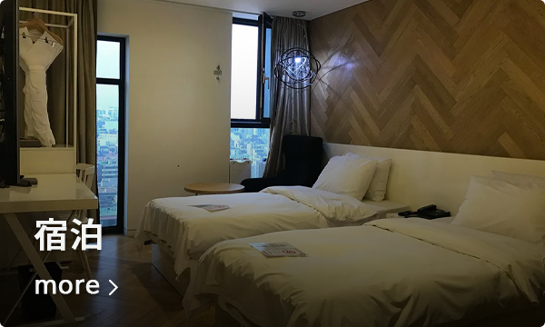 江南エリアにあるホテルの客室内風景。ベッドが二つ並び、窓からはソウルの夜景が見える。