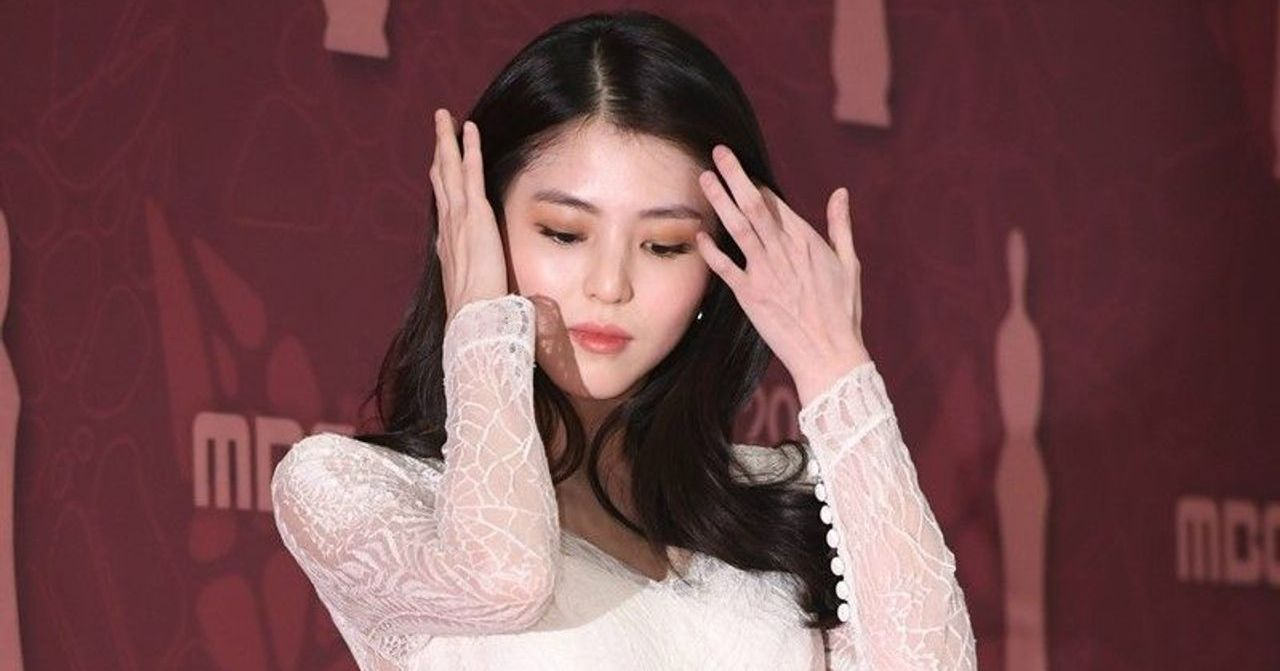 身穿白色複雜蕾絲長裙的女士在紅毯上，展現華麗的紅毯造型