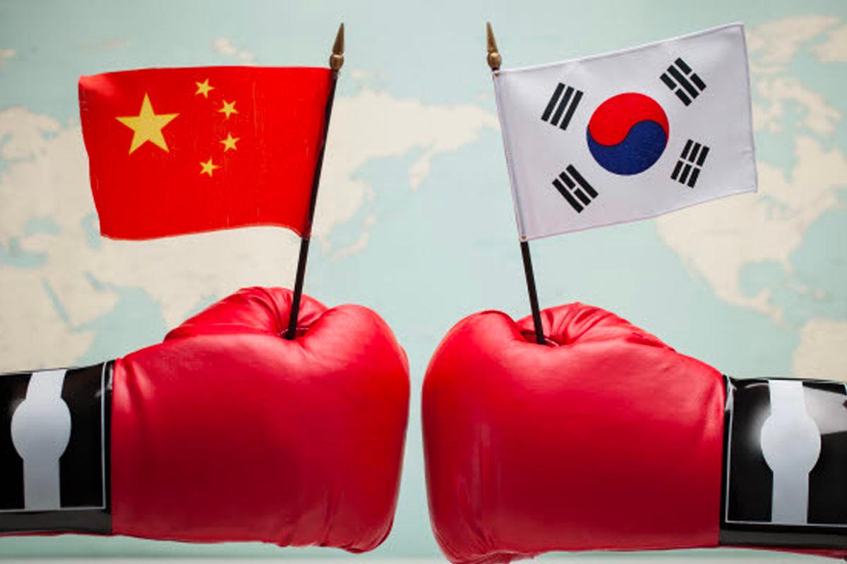 中國與韓國間的競爭，兩隻戴著拳擊手套的手分別拿著中國和韓國國旗，背景為世界地圖，象徵雙方的競爭。