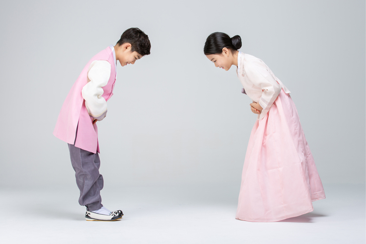 兩個穿著傳統韓服的小朋友正在鞠躬，展示韓國的問候禮儀。