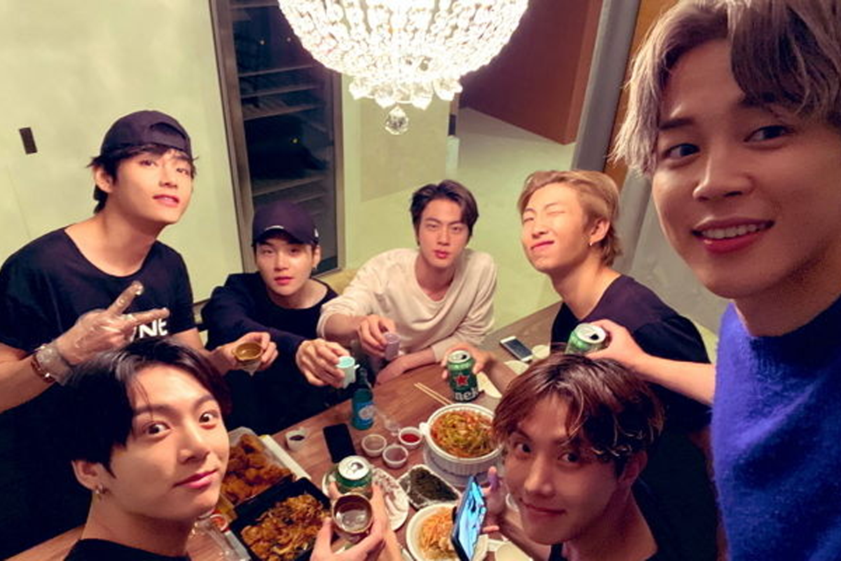 多人聚集在家庭聚會中，桌上擺滿了韓國食物和酒精飲品，展現出韓國的社交文化。