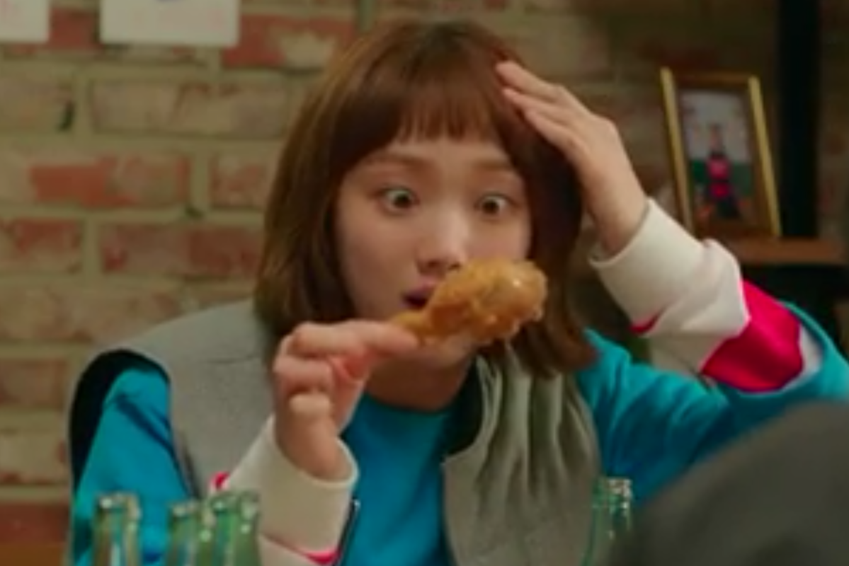 一個人手持炸雞的特寫，象徵著韓國著名的炸雞文化。