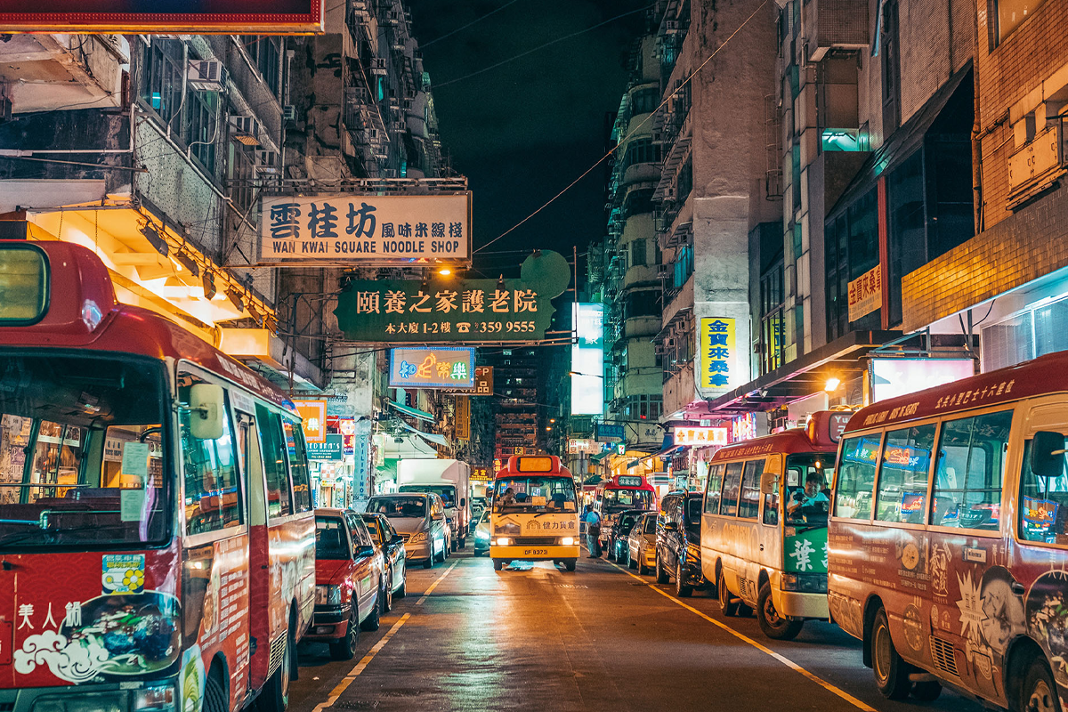 晚上香港街道的景象，包含了多個小巴和光亮的街道招牌，展示了香港的繁華夜生活。