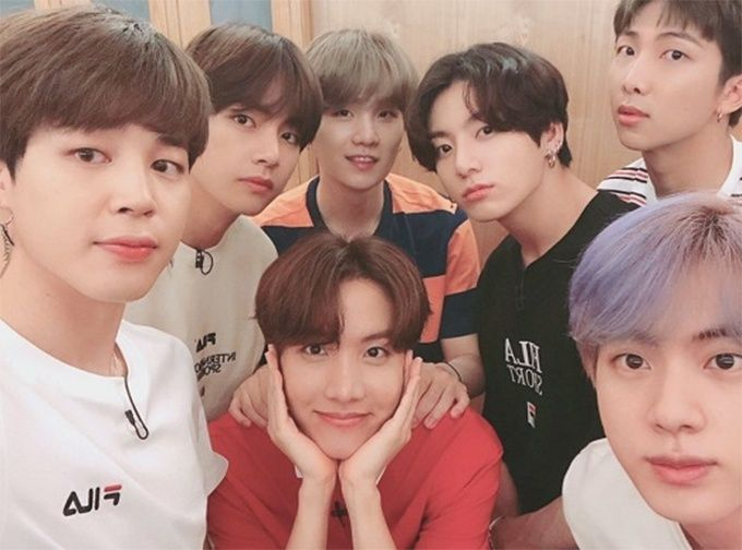 ภาพกลุ่มวัยรุ่นเกาหลีใต้ในห้องหนึ่งใส่เสื้อกีฬาแบรนด์ FILA นั่งถ่ายภาพร่วมกันอย่างเป็นกันเอง