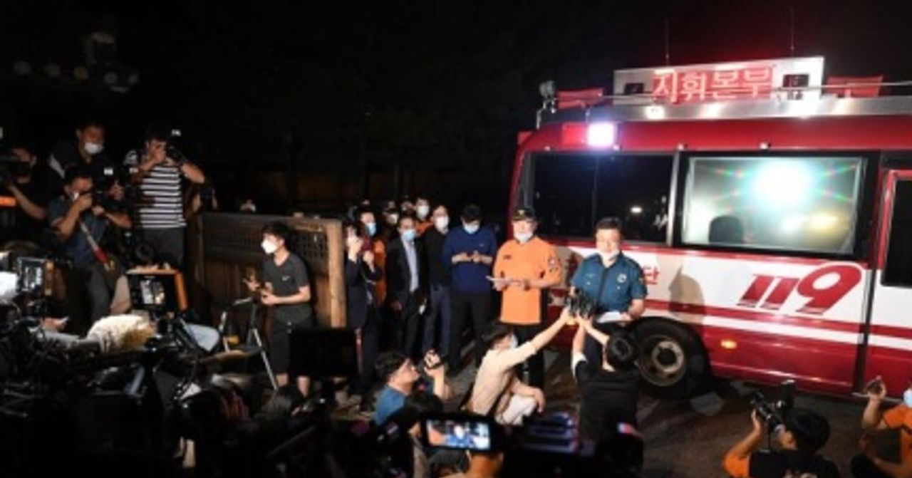 夜間，新冠肺炎相關新聞報導現場，記者們聚集在消防車旁，兩名人員正在接受採訪。