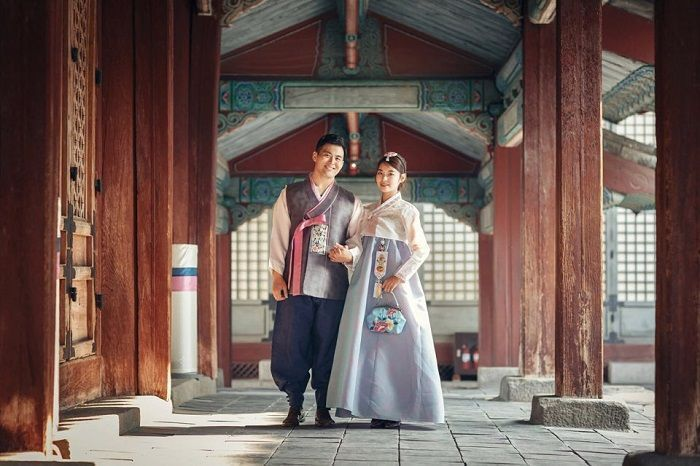 Một cặp đôi đang mặc hanbok truyền thống của Hàn Quốc đi dạo trong khung cảnh cổ điển.