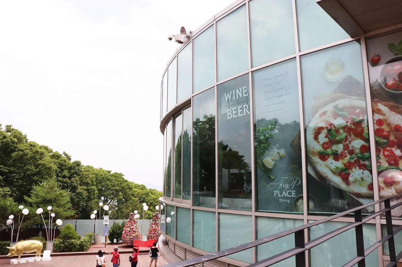 Nhà hàng THE PLACE với mặt kính lớn và dòng chữ Wine & Beer tại N Seoul Tower, Hàn Quốc.