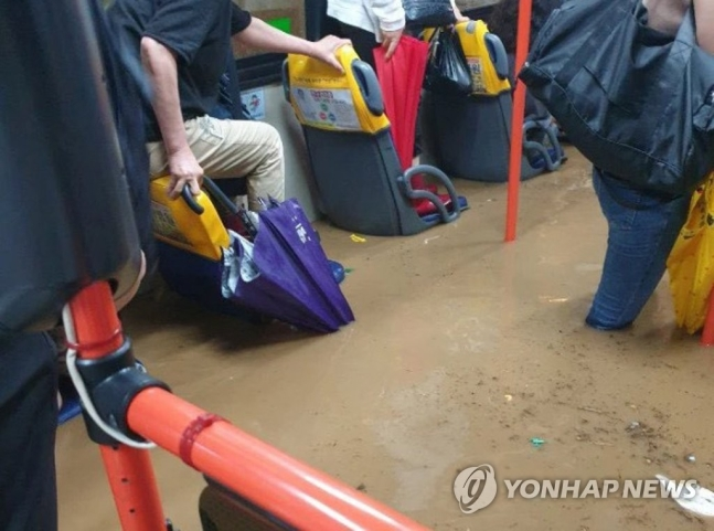 🔴 公車因暴雨水淹而積水,乘客服持手提雨傘站立在座位間