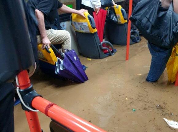集中豪雨による釜山の冠水したバス車内。市民たちが水に囲まれながら傘を持って座っている様子。