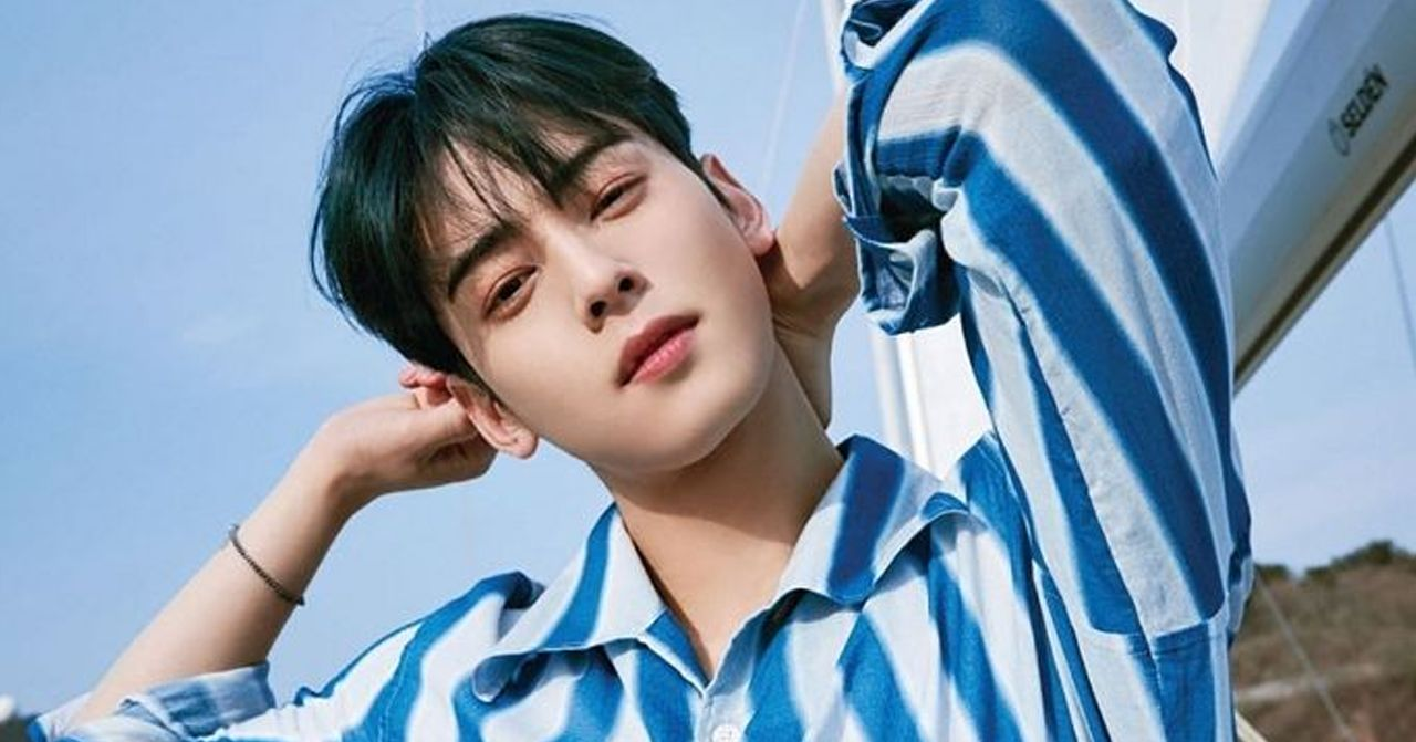 藍天白雲下，一個穿著藍白條紋襯衫的男性在陽光下，背景似乎是户外旅遊場所，給人一種自由和輕鬆的感覺。