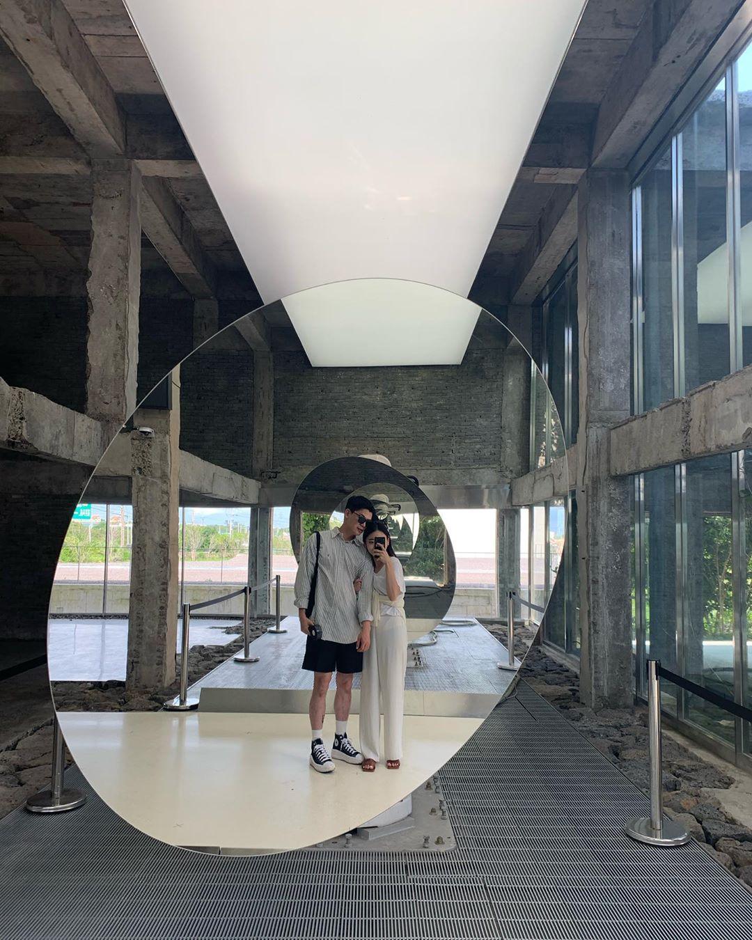 コンベクカフェのアートギャラリーでスタイリッシュなフォトゾーン。円形の鏡と高い天井が印象的な現代的な展示空間。