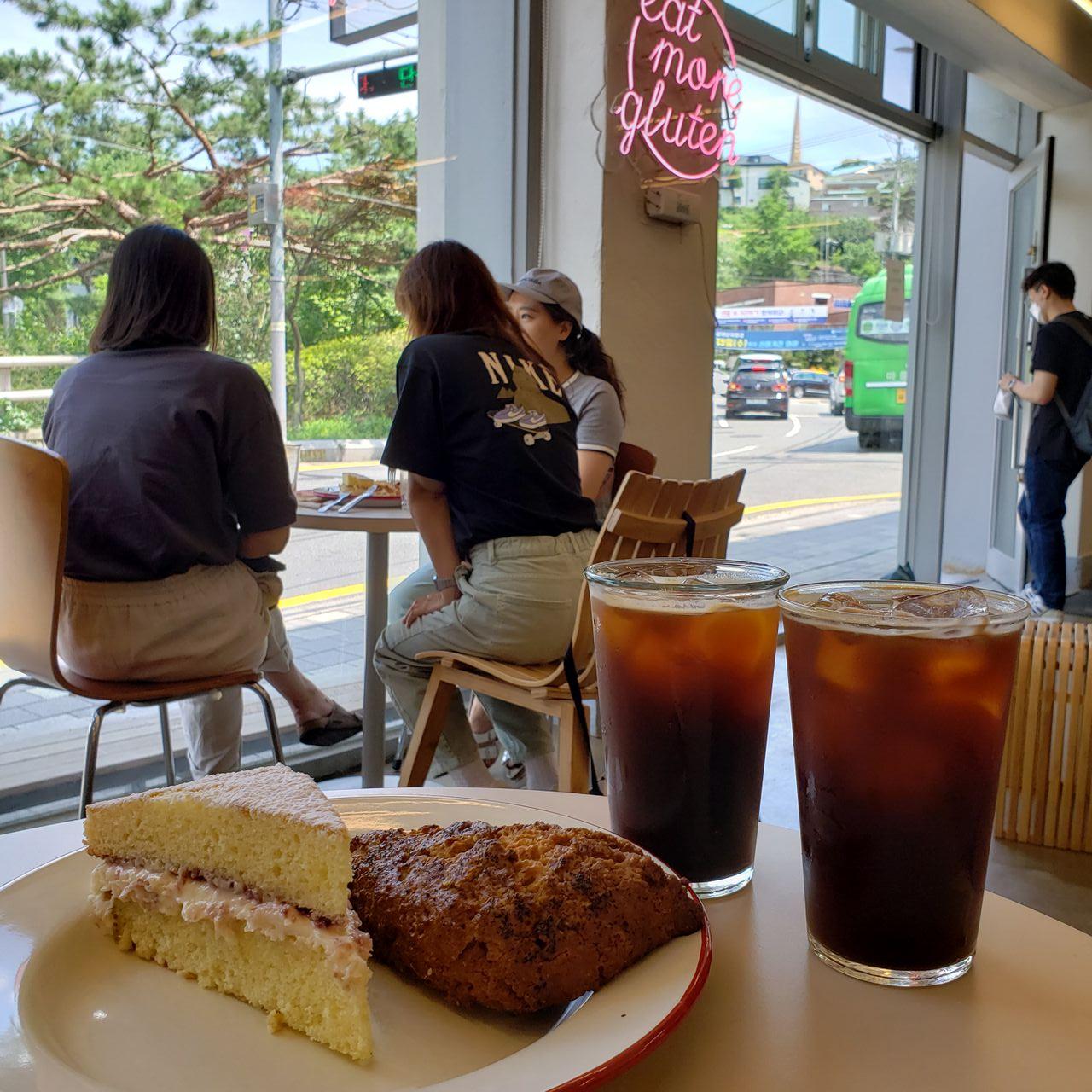 กาแฟกับเค้กที่น่าทานในคาเฟ่เกาหลี ตกแต่งด้วยไฟสีสันและโต๊ะสำหรับนั่งพูดคุย ตัวอย่างบรรยากาศร้านกาแฟในเกาหลี