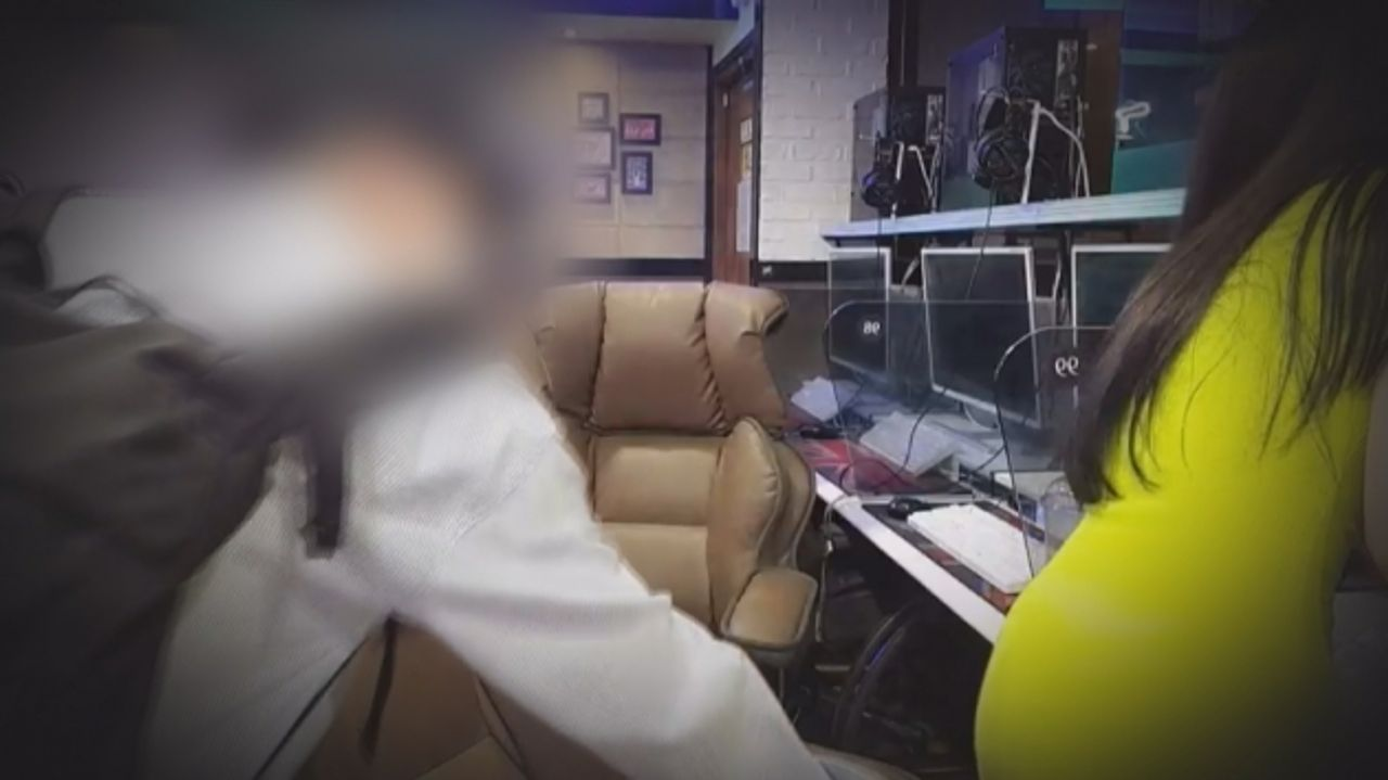 韓國網吧內，一名顯示為偷拍受害者的女性身穿彩色衣服在工作區域內清潔，周圍擺放著多臺電腦。