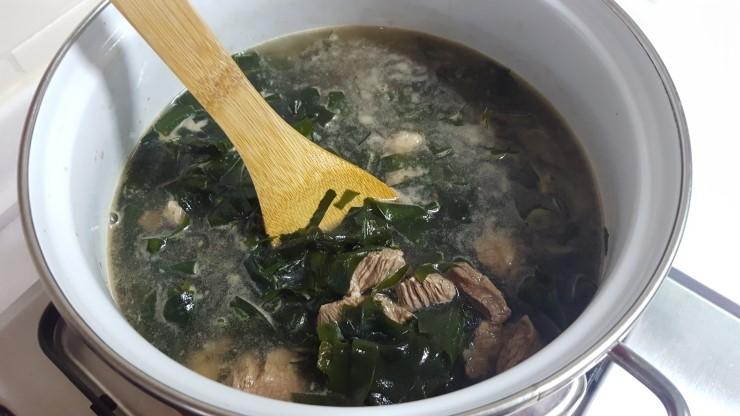 グッカンジャンを使用して味付けされたわかめスープが鍋で調理されている。木製の調理道具を使って料理をかき混ぜる。