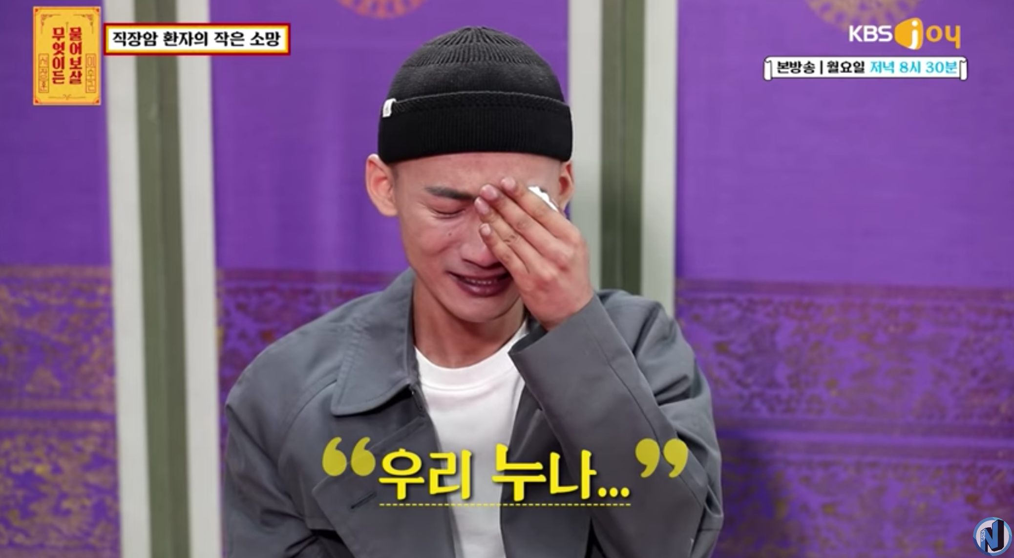 穿著官服的人正在電視節目中流淚,背後背景有紫色的裝飾佈景,顯示衝擊的情感表達