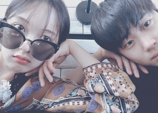 兩位穿著花色服裝的人坐在一起，其中一人佩戴白色花飾品。