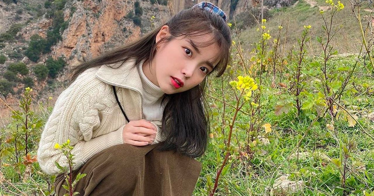 ผู้หญิงในชุดเสื้อไหมพรม คุกเข่าท่ามกลางดอกไม้ป่าในทุ่งหญ้า สำหรับบทความเกี่ยวกับการแต่งกายกลางแจ้งในเกาหลี