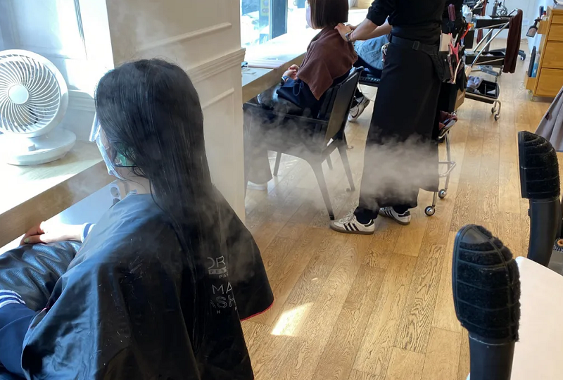 韓国の美容室風景、窓際に座る客とスタイリストの後ろ姿。