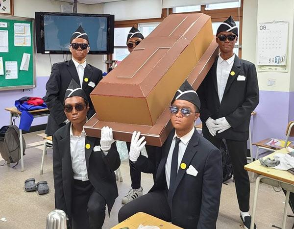 義政府高校の卒業写真で棺桶を持ってパロディーを演じる生徒たちの姿。