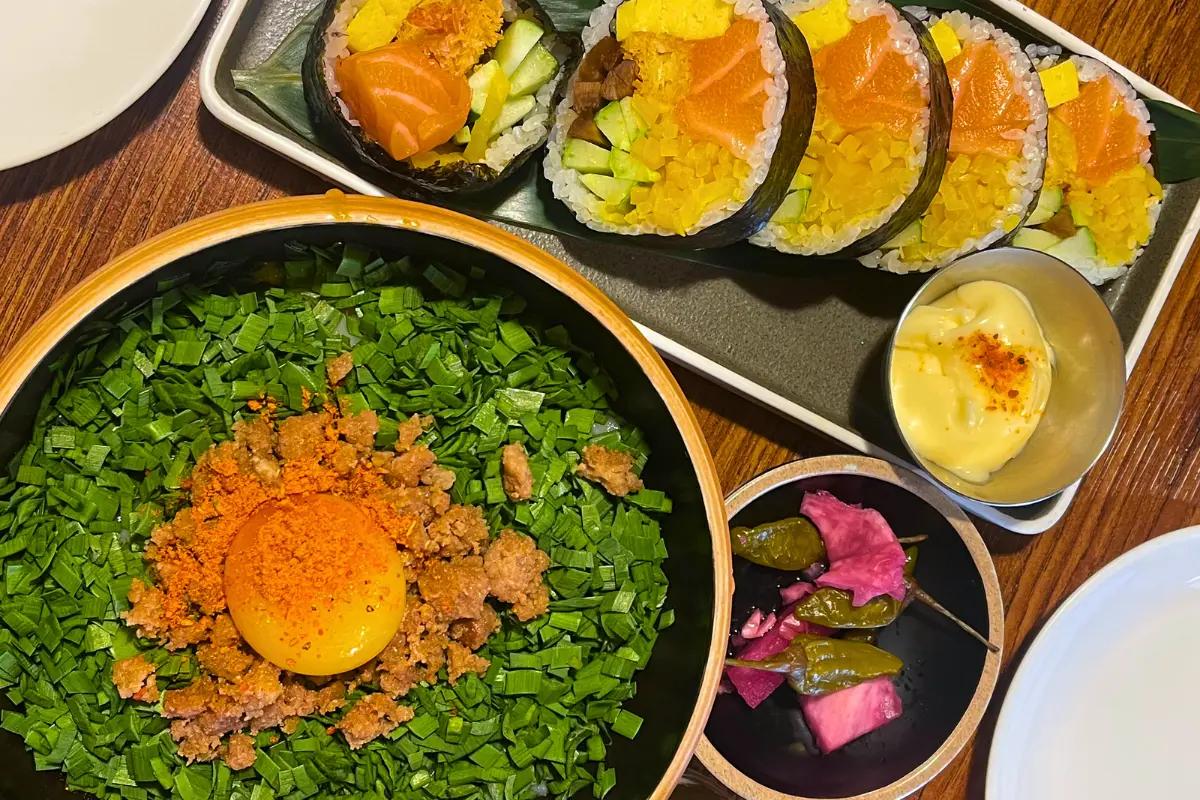 A plate of Salmon Futomaki rolls paired with a bowl of Mazesoba noodles topped with a raw egg yolk at Choi Dining in Seongsu, Seoul.