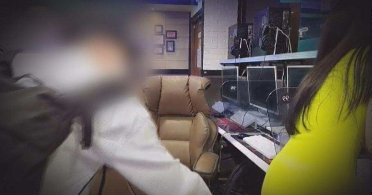 韓國某網咖內部景象，顯示電腦設備和椅子的佈局，背景中還看到貼有遊戲的海報。