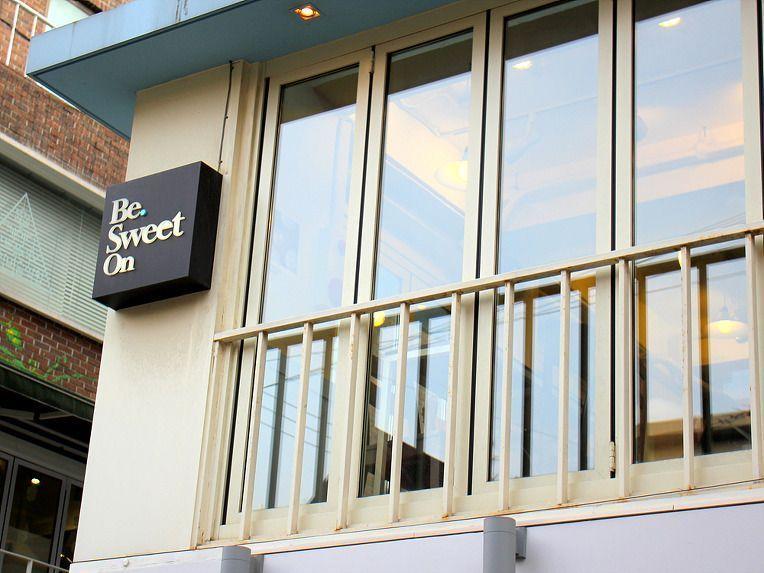 Be Sweet On咖啡廳的外觀，簡約的設計和白色的牆壁搭配木質的裝修風格，旨在吸引行人目光。
