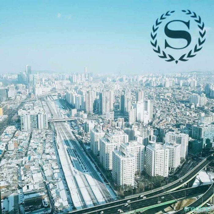 從高空俯瞰首爾城市天際線，遠處的摩天大樓和雪白的地面給予人一種繁忙與靜謐並存的對比。