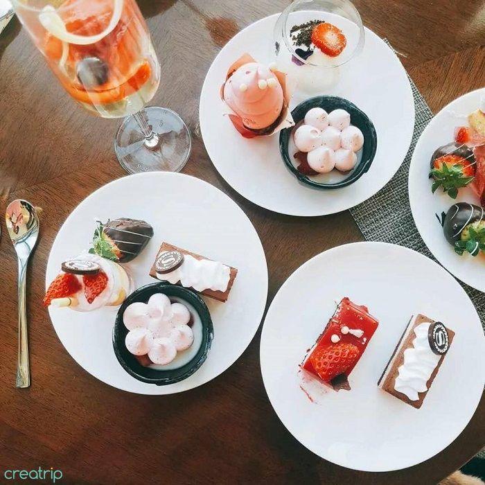 桌上的多款草莓甜點，盤中擺著各式不同形狀的甜點，與誘人的草莓一同散發香甜氣息。