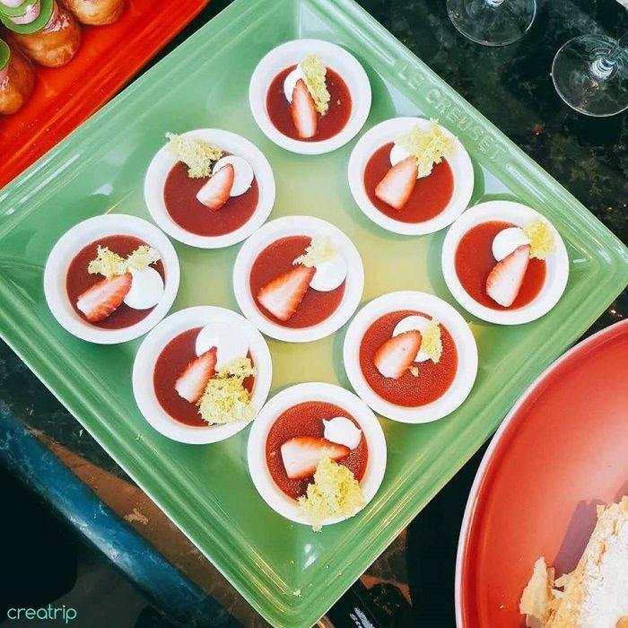 餐盤上擺放著幾碗草莓甜點，白色慕斯上鋪著新鮮草莓片，配上鮮奶油，視覺上鮮艷誘人。