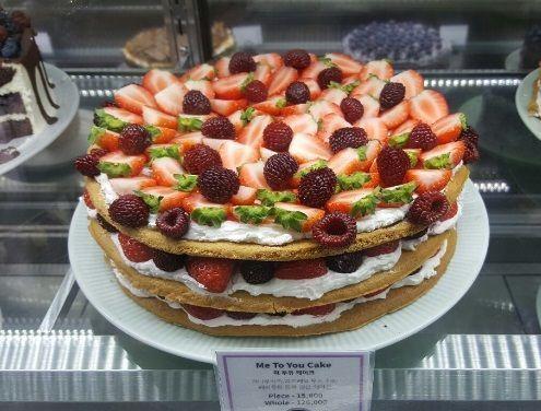 展示櫃中的草莓和覆盆子蛋糕，每一層都鋪滿新鮮水果，令人垂涎欲滴。