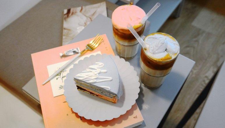 桌上的蛋糕與升騰的拿鐵，豐富的色彩與飲品的鮮奶油形成完美搭配，視覺效果滿分。