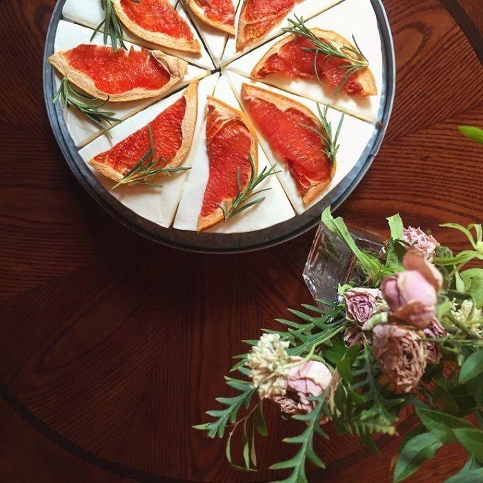 切成八片的葡萄柚裝飾蛋糕，放在一個圓形託盤上，旁邊放著一花束，使整個擺盤優雅又精緻。