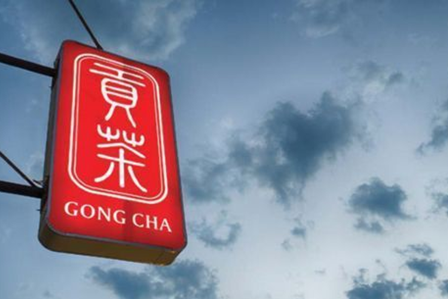 貢茶户外招牌，紅色背景上有白色字樣的貢茶標誌，招牌在藍天白雲下顯得特別顯眼，代表著這一受歡迎的飲品品牌。