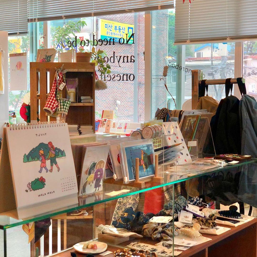 韓国雑貨店のショーケースに展示されたカラフルな靴下とスマホケース。多様なデザインのアイテムが窓からの景色をバックに並べられている。