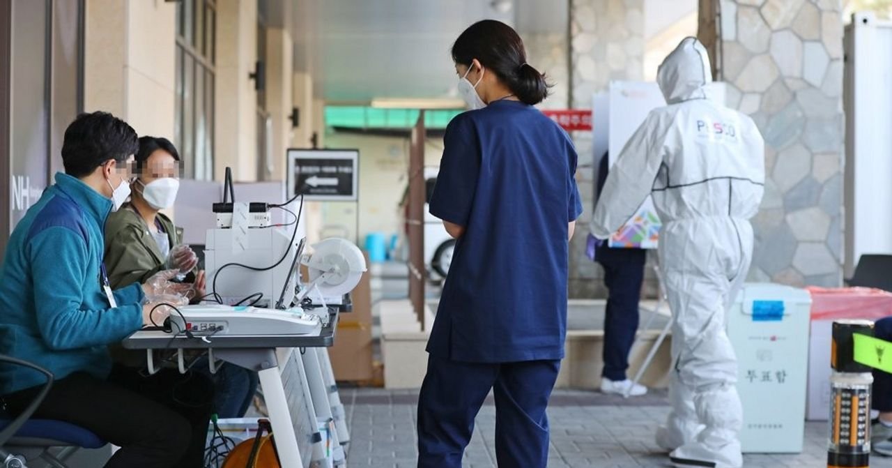 韓國新冠病毒檢測站，醫護人員和民眾在準備進行病毒檢測，桌上擺放著檢測設備。