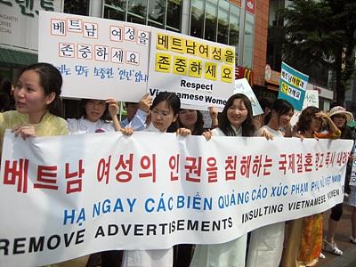 Một nhóm người tổ chức biểu tình đòi tôn trọng quyền phụ nữ Việt Nam tại Hàn Quốc, với các biểu ngữ và bảng hiệu ghi bằng tiếng Việt và tiếng Hàn.