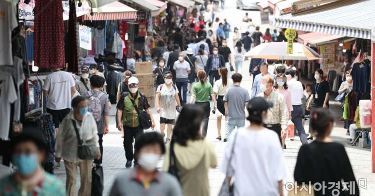 ภาพผู้คนสวมหน้ากากเดินทางในตลาดเกาหลีในช่วงการแพร่ระบาดของโควิด-19