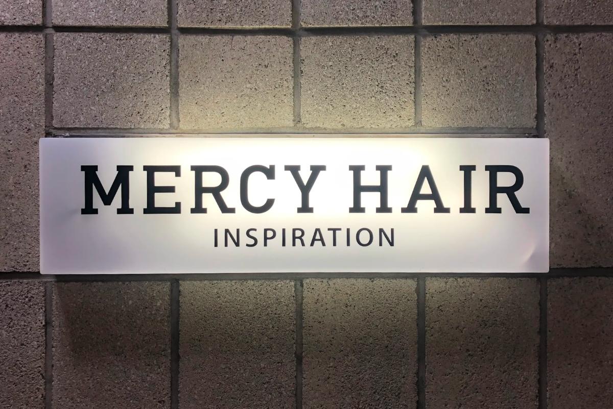 Cartel de Mercy Hair en la entrada, un famoso salón de belleza en Seúl, cerca de la Universidad Kyung Hee, conocido por sus estilos innovadores y diseño moderno.